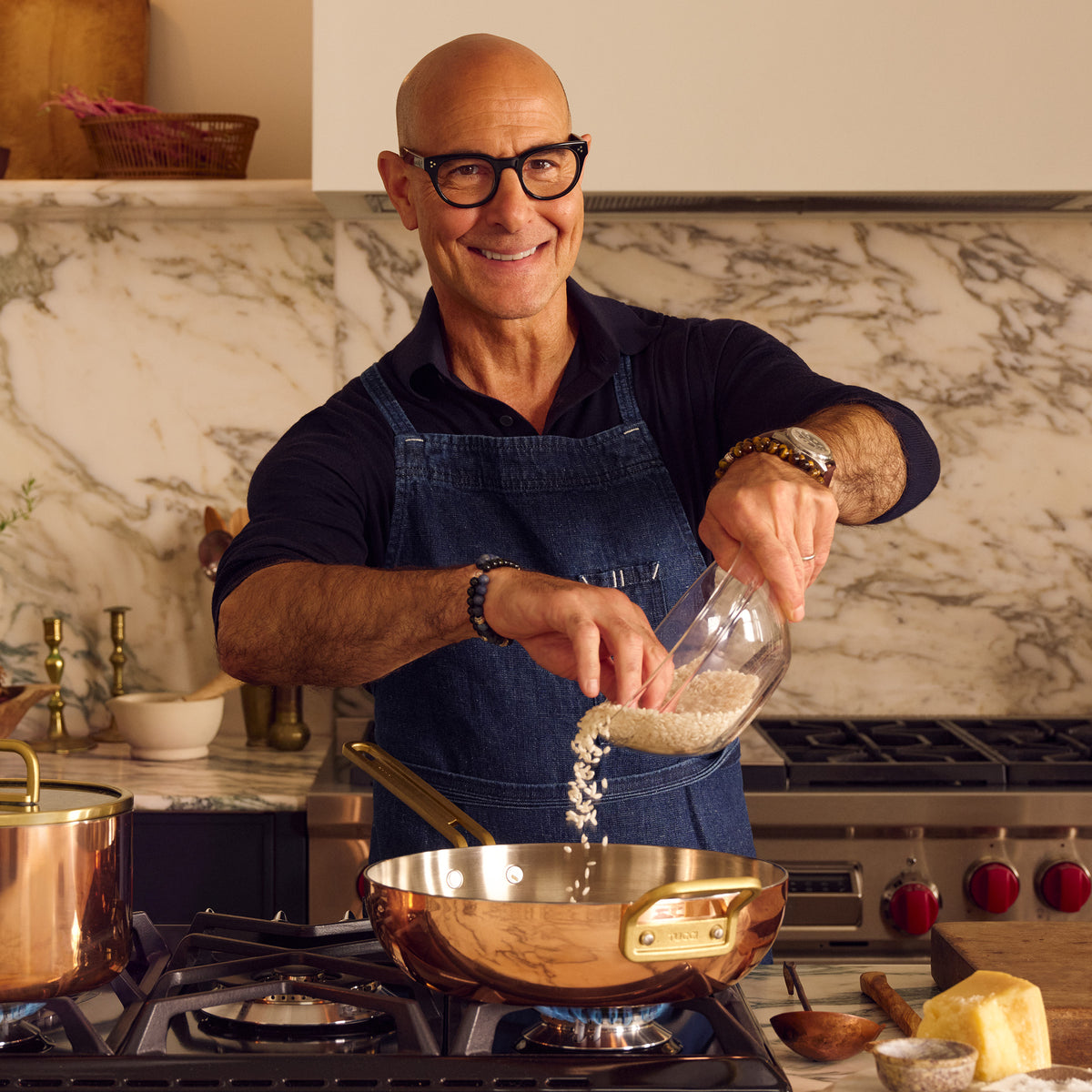 Man pours rice into a copper Stanley Tucci 4.5-quart pan on the stove in a modern kitchen.