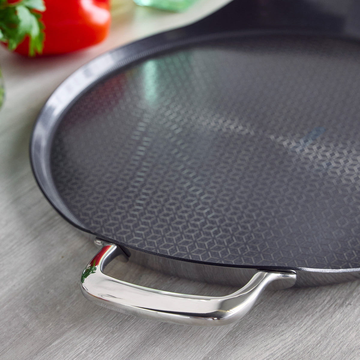 Spectra Thermobond 13″ round ceramic nonstick griddle with a textured geometric surface and a polished stainless steel side handle.