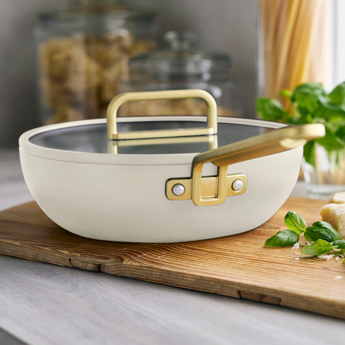 Stanley Tucci 3.25qt Piccolo Pan in Carrara White with a matching lid and gold handles, placed on a wooden board.