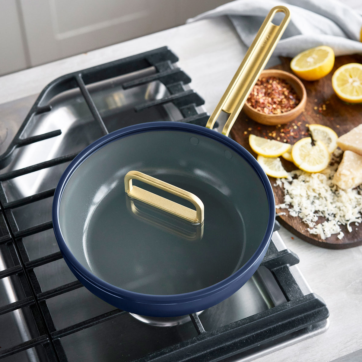 Stanley Tucci 3.25-quart ceramic nonstick piccolo pan in Marino Blue with gold-tone handles on a stovetop.
