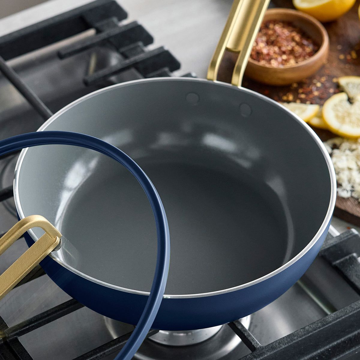 Marino Blue Stanley Tucci 3.25-quart ceramic nonstick Piccolo pan with a gold handle and glass lid on a stovetop.