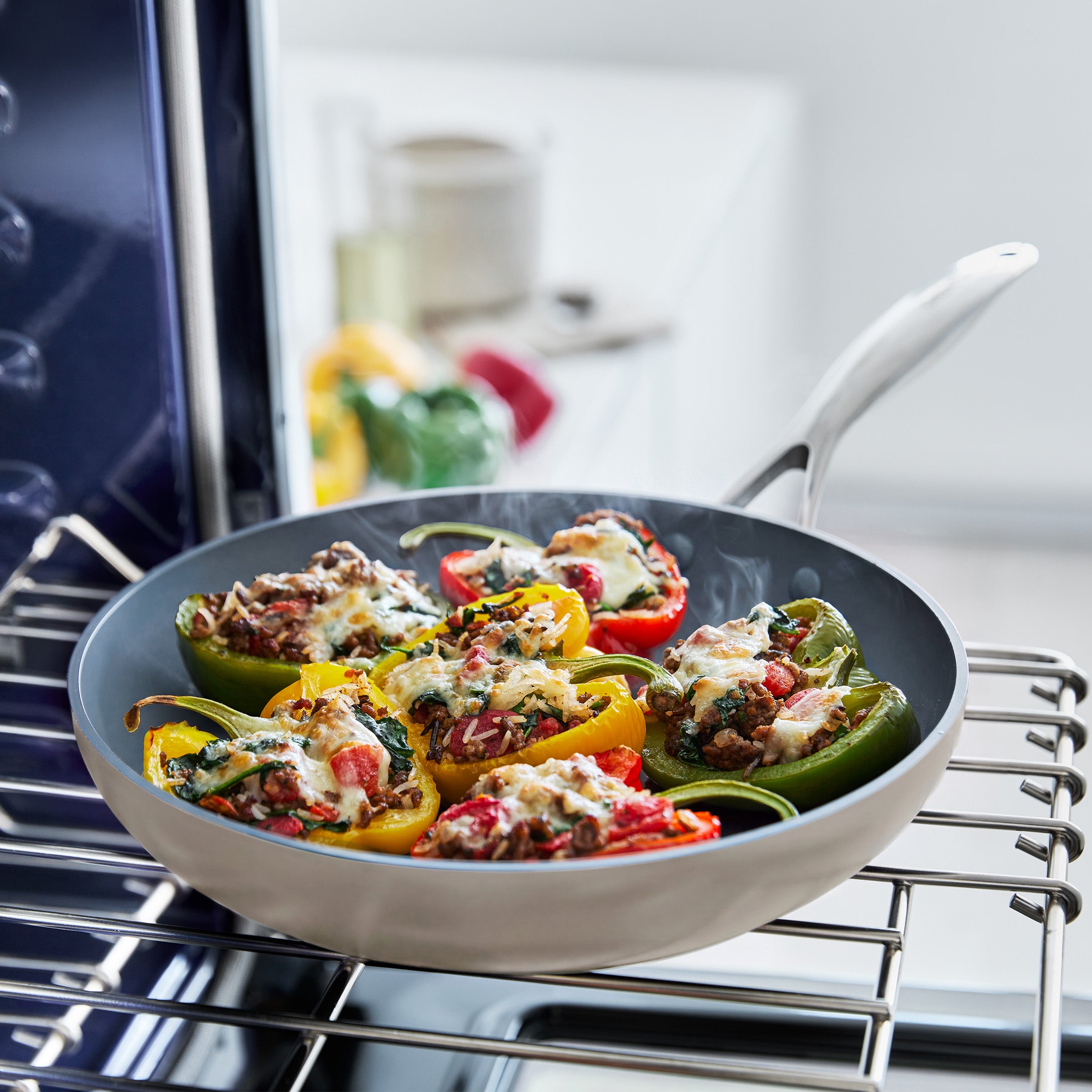 Stuffed peppers with veggies and cheese in a gray ceramic nonstick frypan set, two pans shown on a kitchen surface.