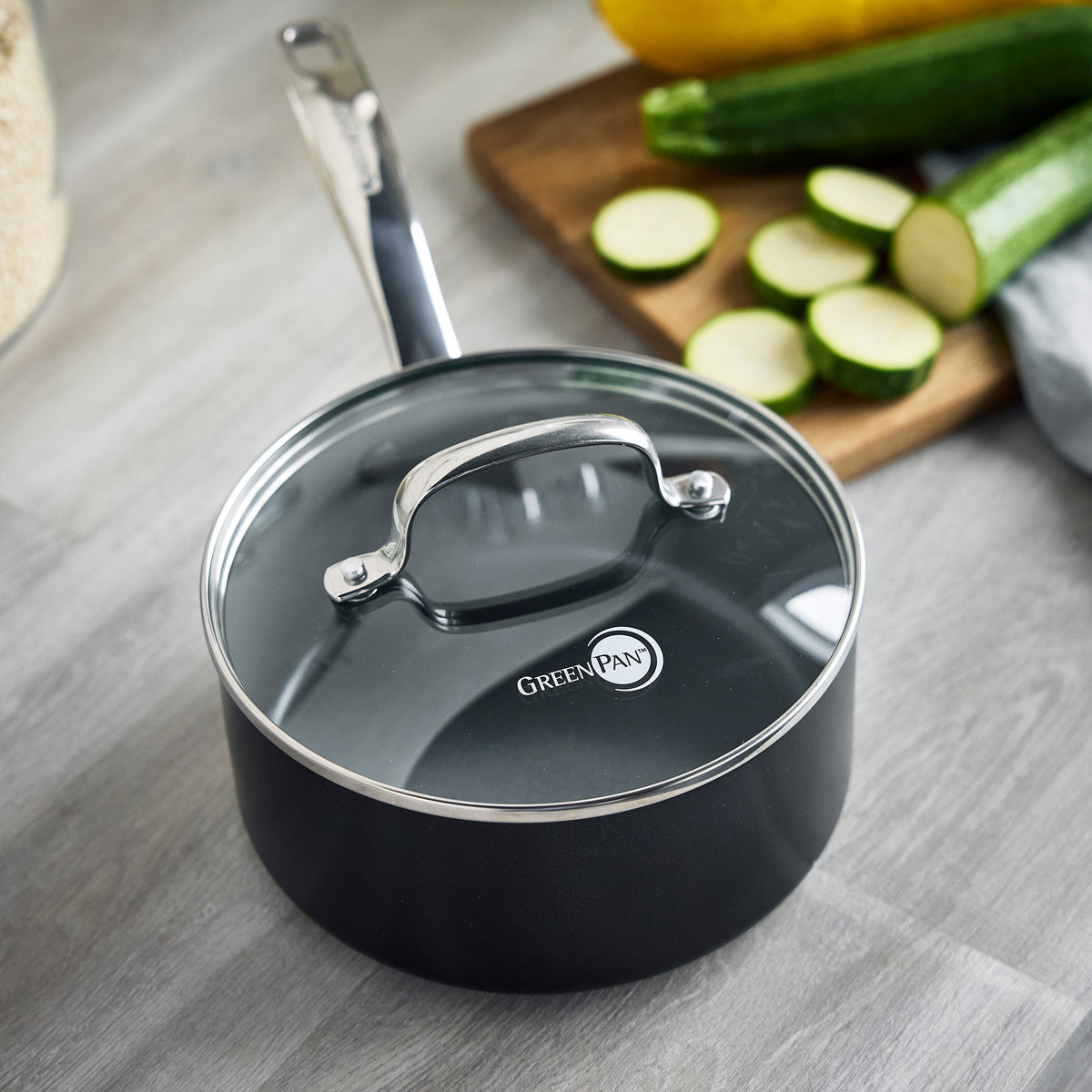 Chatham Pro ceramic nonstick 12-piece cookware set saucepan in black with a glass lid on a gray countertop with sliced zucchini.