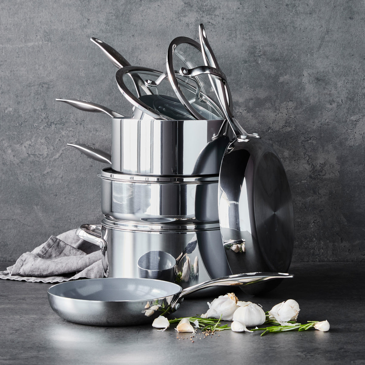 Valencia Pro stainless steel 18-piece cookware set featuring ceramic nonstick pots, pans, and glass lids stacked on a gray surface.