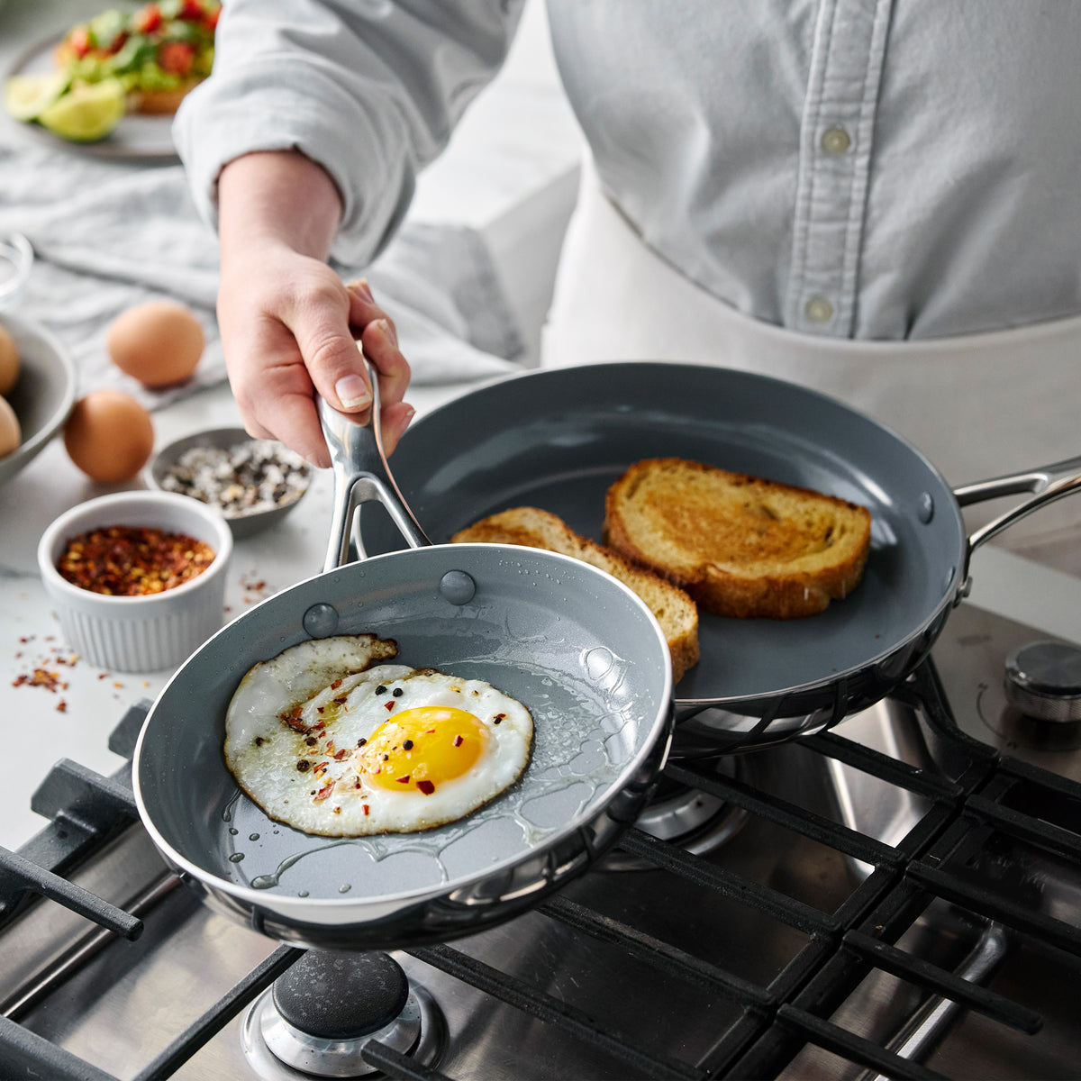 Valencia Pro 18-piece stainless steel cookware set featuring a skillet cooking a fried egg next to a pan with toasted bread.