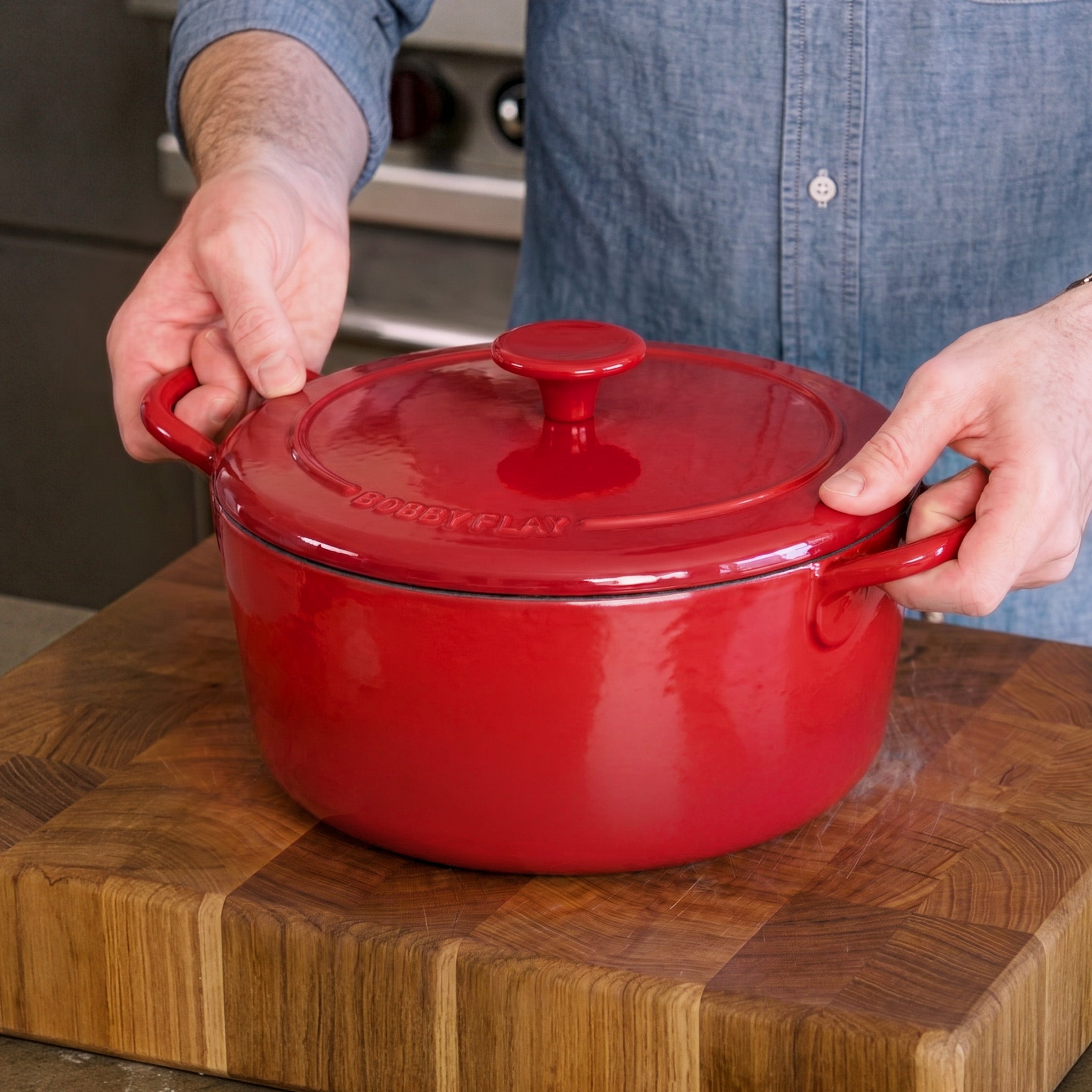 Person holding a red 5.5-quart GreenPan Dutch oven with handles and lid.