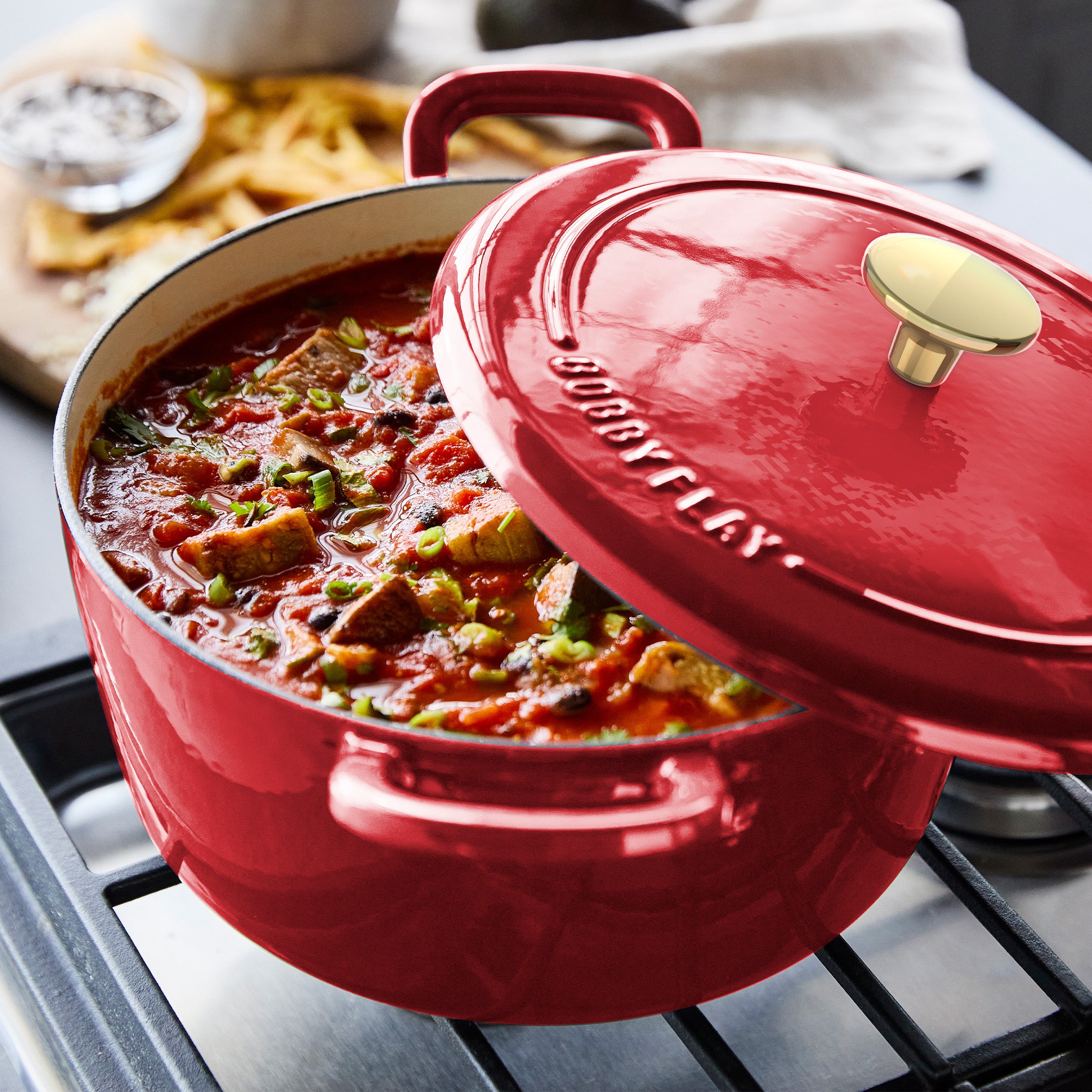 Red enameled cast iron Dutch oven set by GreenPan, 5.5-quart capacity, includes lid and accessory, shown on white background.