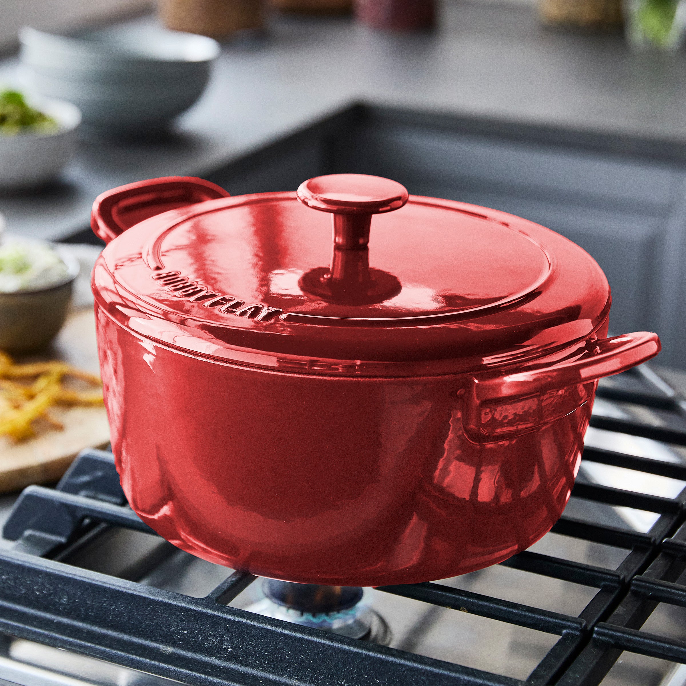 Red 5.5-quart Dutch oven with lid on a stovetop in a modern kitchen setting.