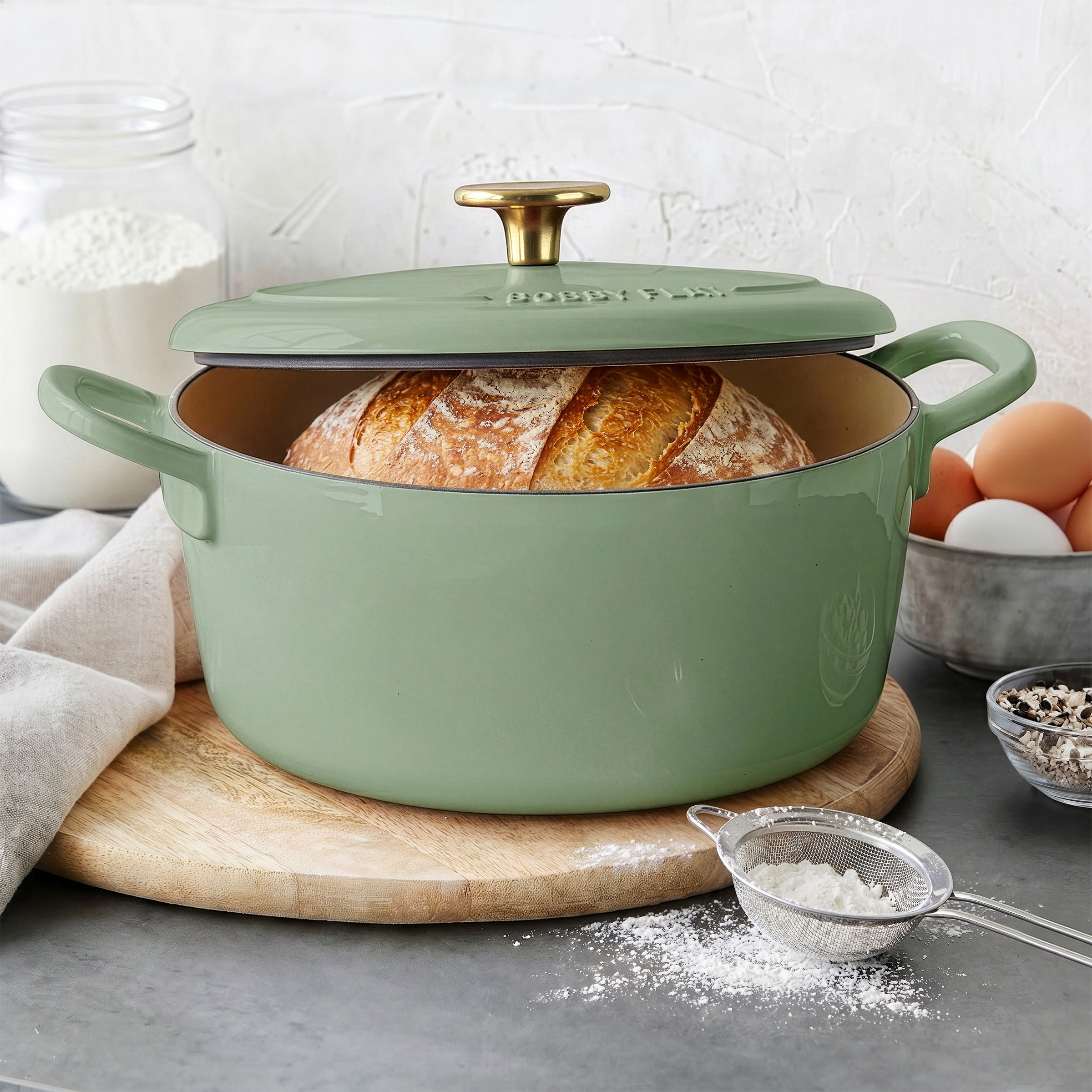 GreenPan sage green 5.5-quart Dutch oven set with lid and utensil, ceramic material, three pieces shown together.