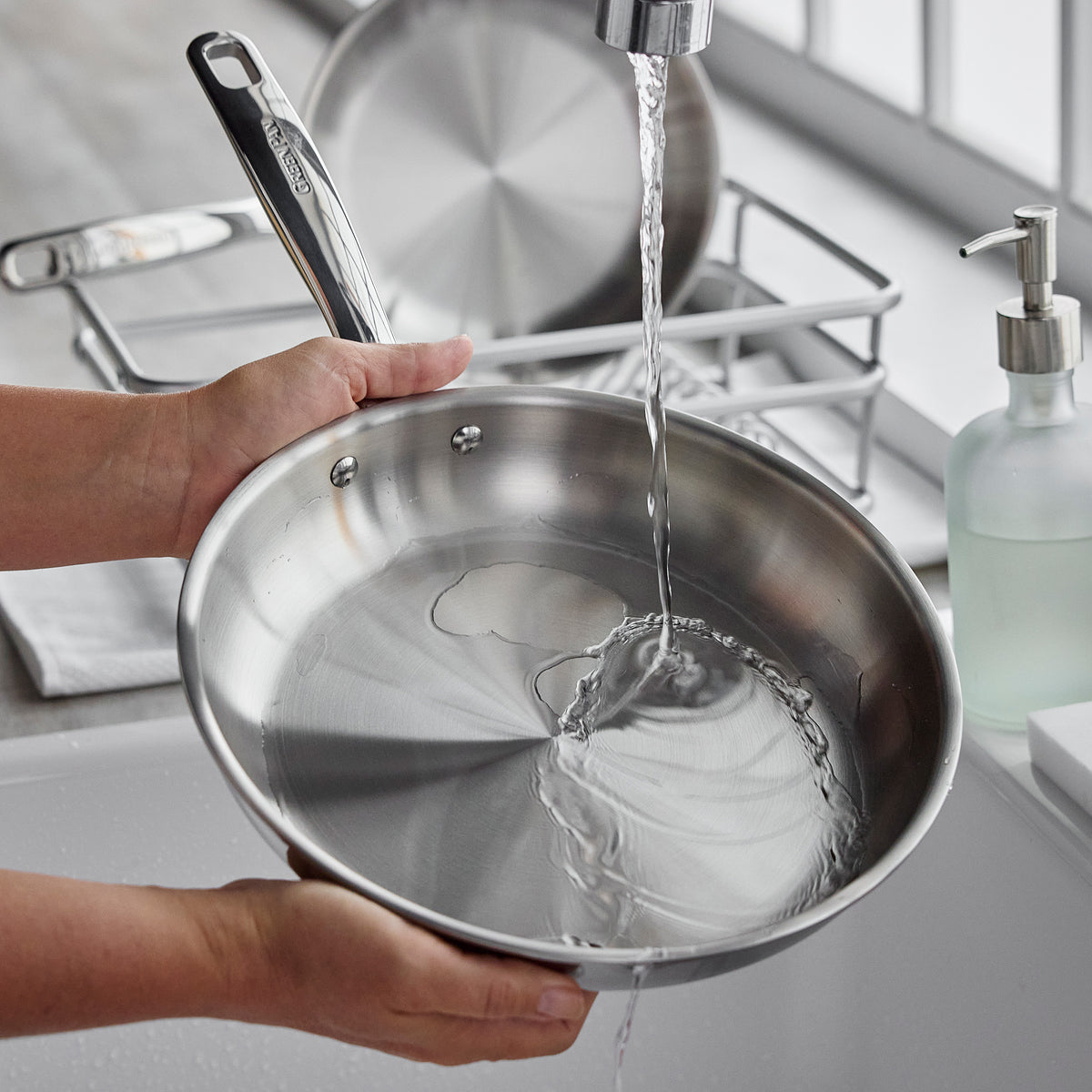 Chatham Pro 12-inch stainless steel frypan being rinsed under a kitchen faucet.