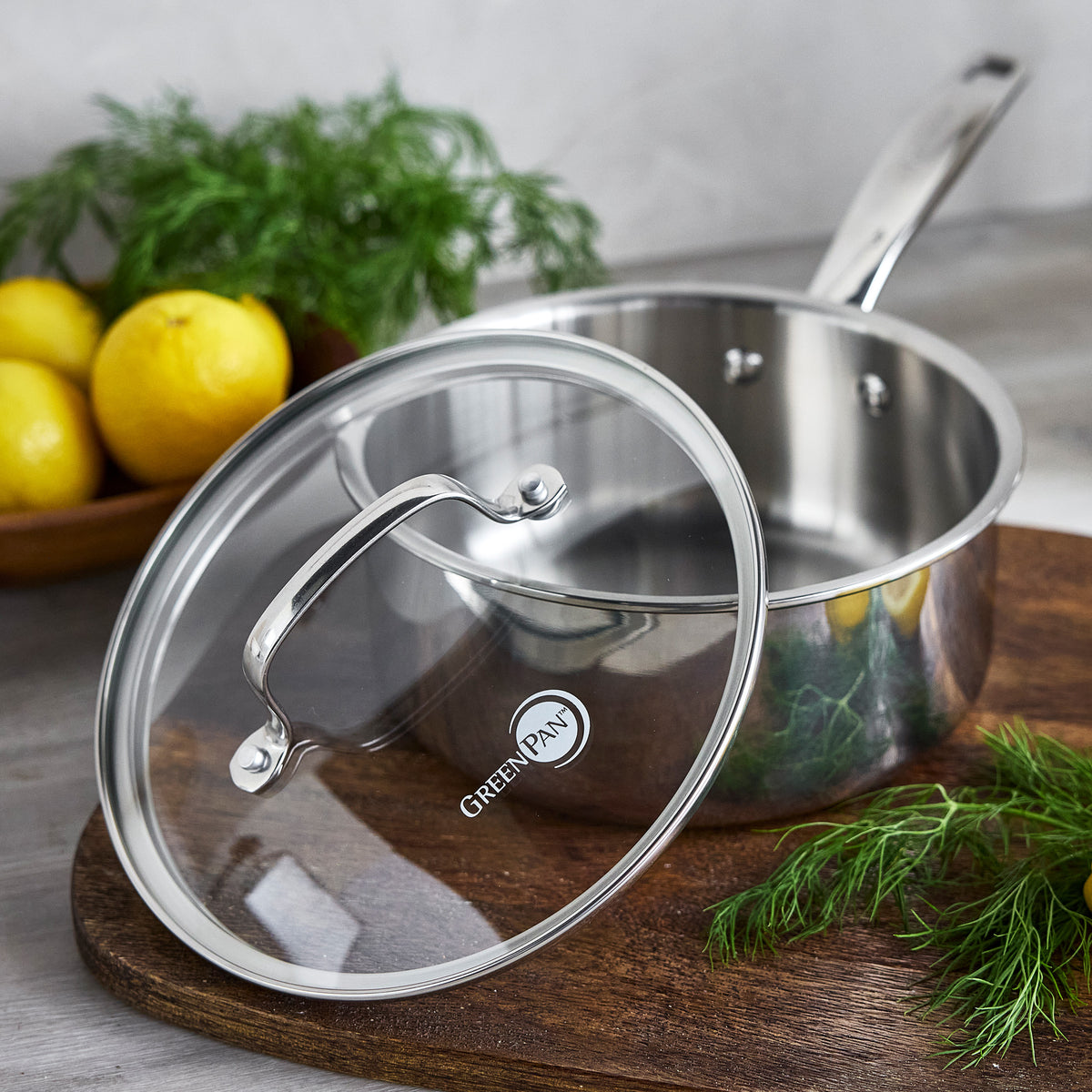 Chatham Pro 12-piece stainless steel saucepan with a glass lid on a wooden cutting board.