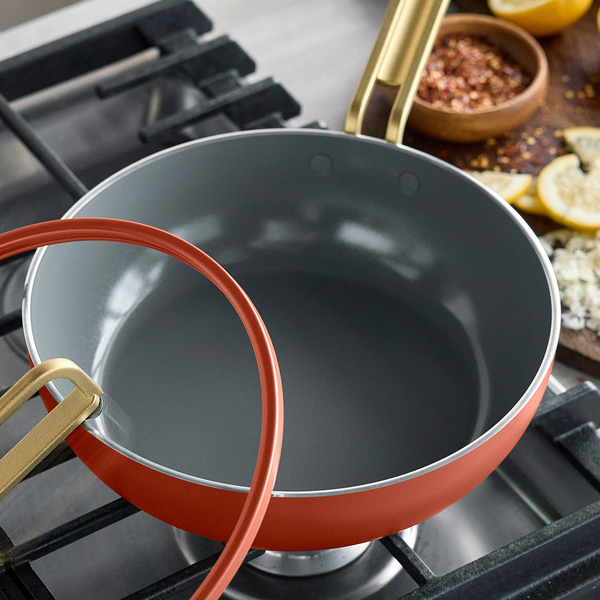 Amalfi Sunset Stanley Tucci™ 3.25-quart ceramic nonstick piccolo pan with a gold handle and detached lid on a stovetop.