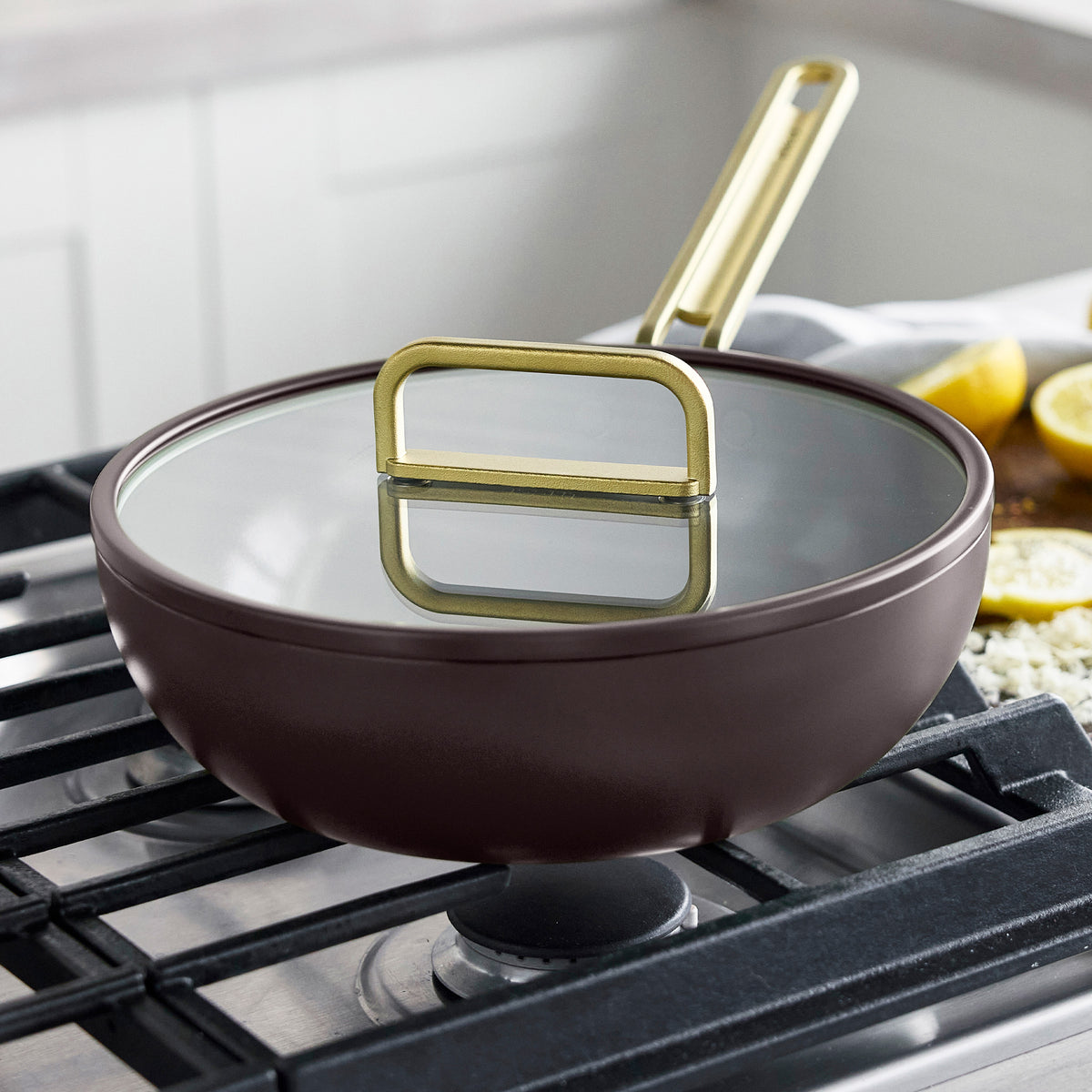 Stanley Tucci 3.25-quart espresso ceramic nonstick Piccolo pan with a glass lid and gold handles on a stovetop.