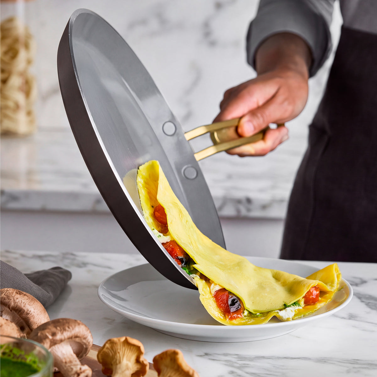 Stanley Tucci™ 10″ ceramic nonstick crepe and omelette pan in espresso sliding a tomato omelette onto a white plate.