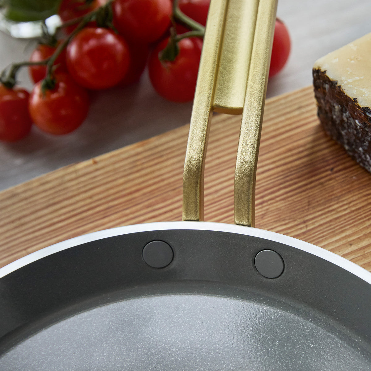Stanley Tucci 10-inch ceramic nonstick crepe and omelette pan in espresso with a gold-tone handle, set on a board with tomatoes and cheese.