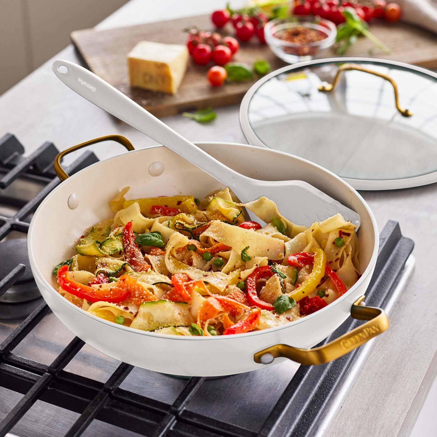 Cream ceramic nonstick everyday pan with cooked pasta and veggies, white spatula inside.
