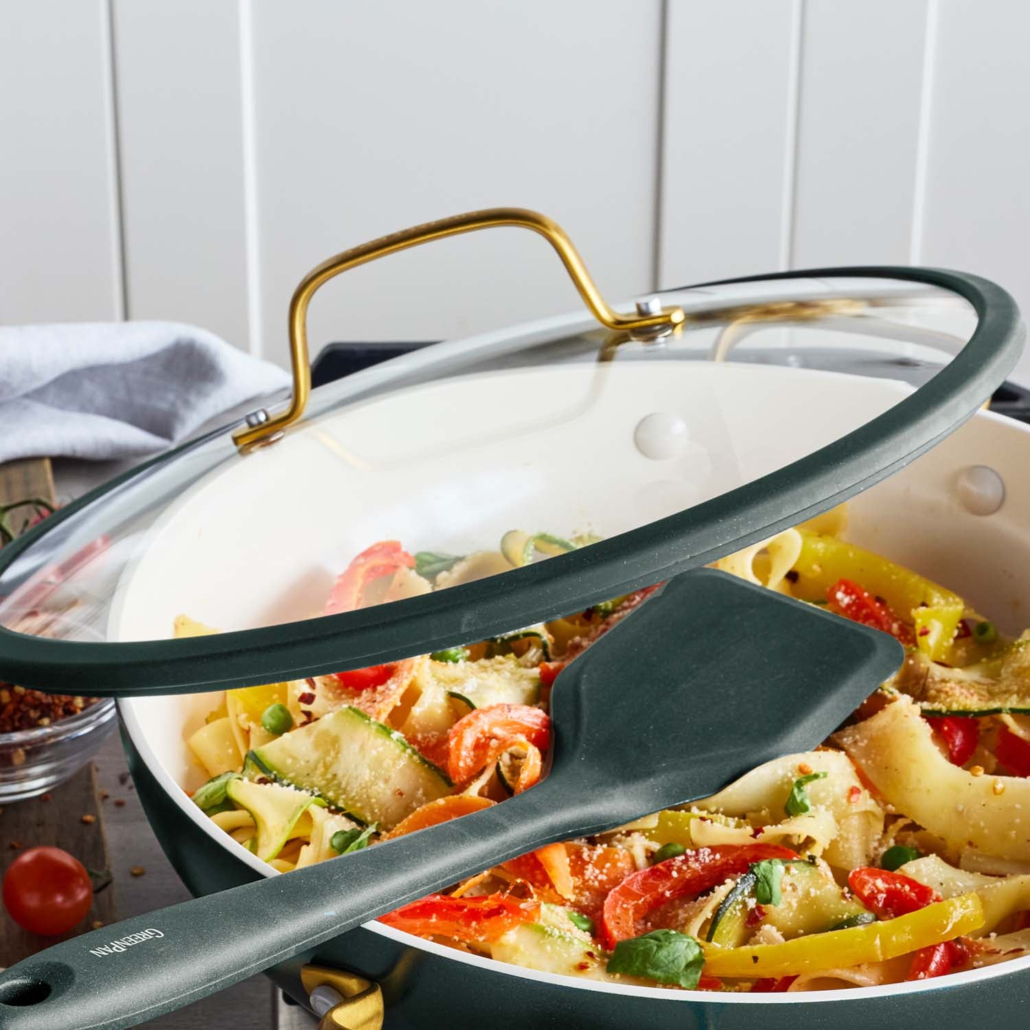Spruce green 3.75-quart everyday pan with lid, filled with pasta and vegetables, on a table.