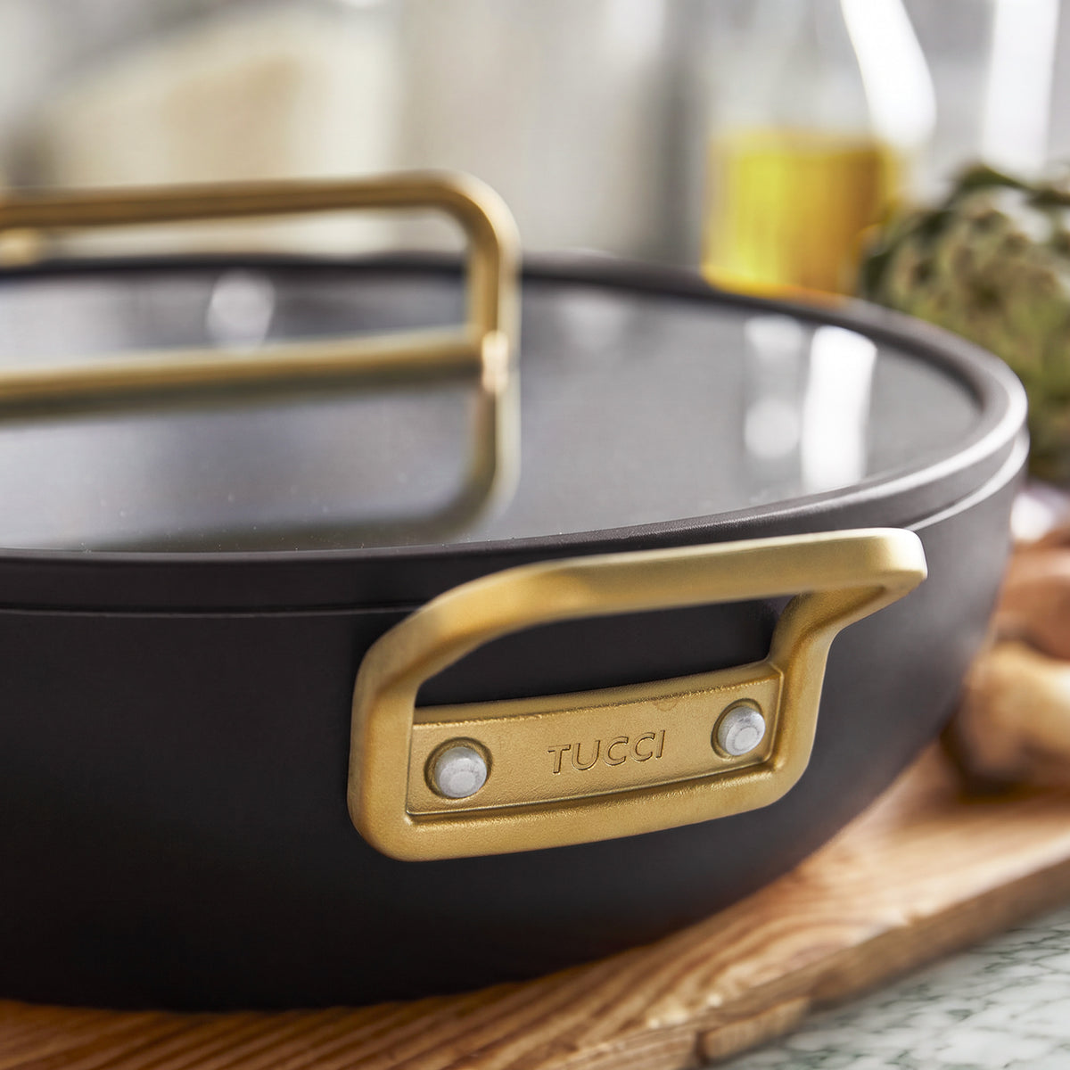 Espresso-colored 6.5-quart Stanley Tucci ceramic nonstick pan with a glass lid and gold-toned metal handles.