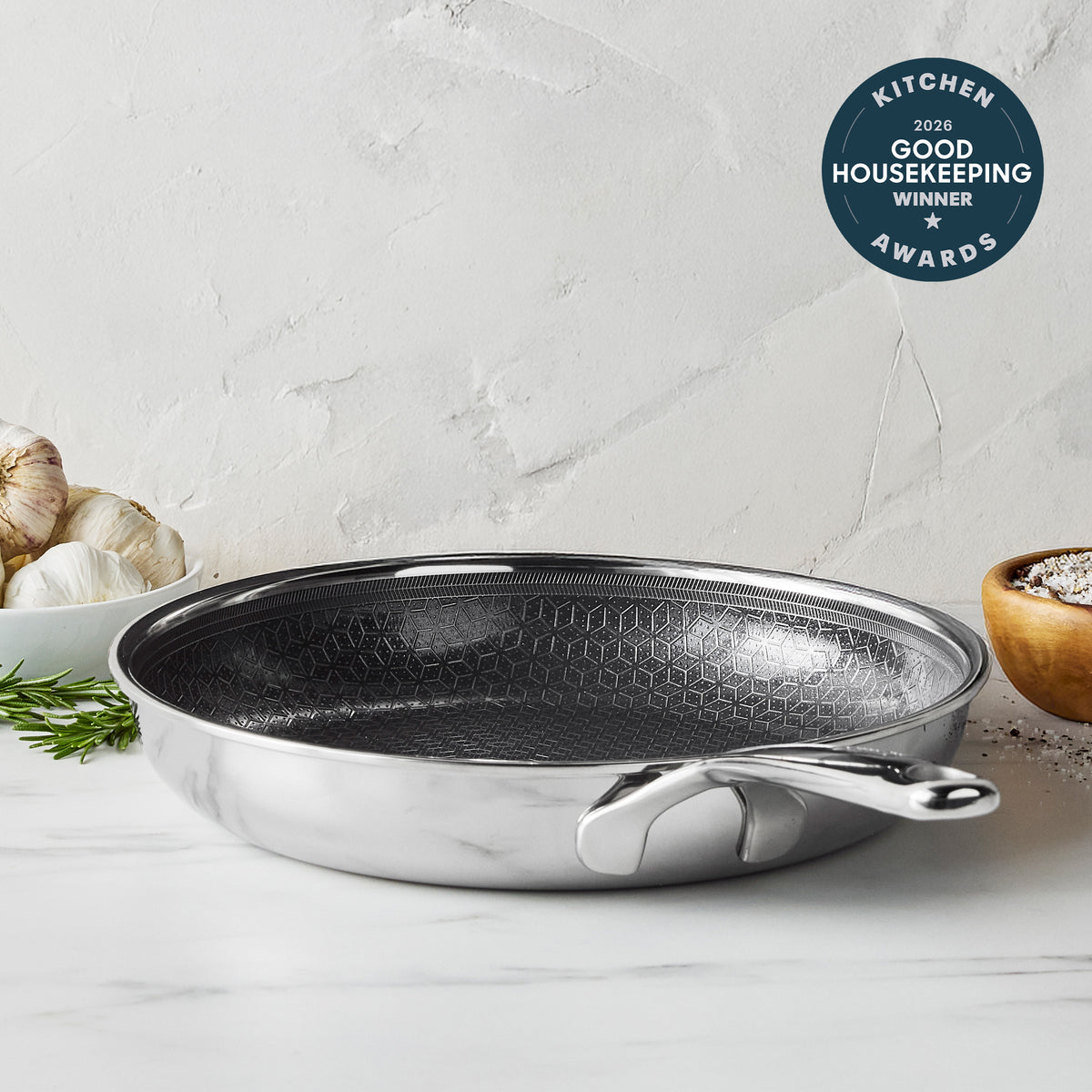 Gray ceramic 10″ frypan on a kitchen counter with garlic, herbs, salt, and an award badge visible nearby.