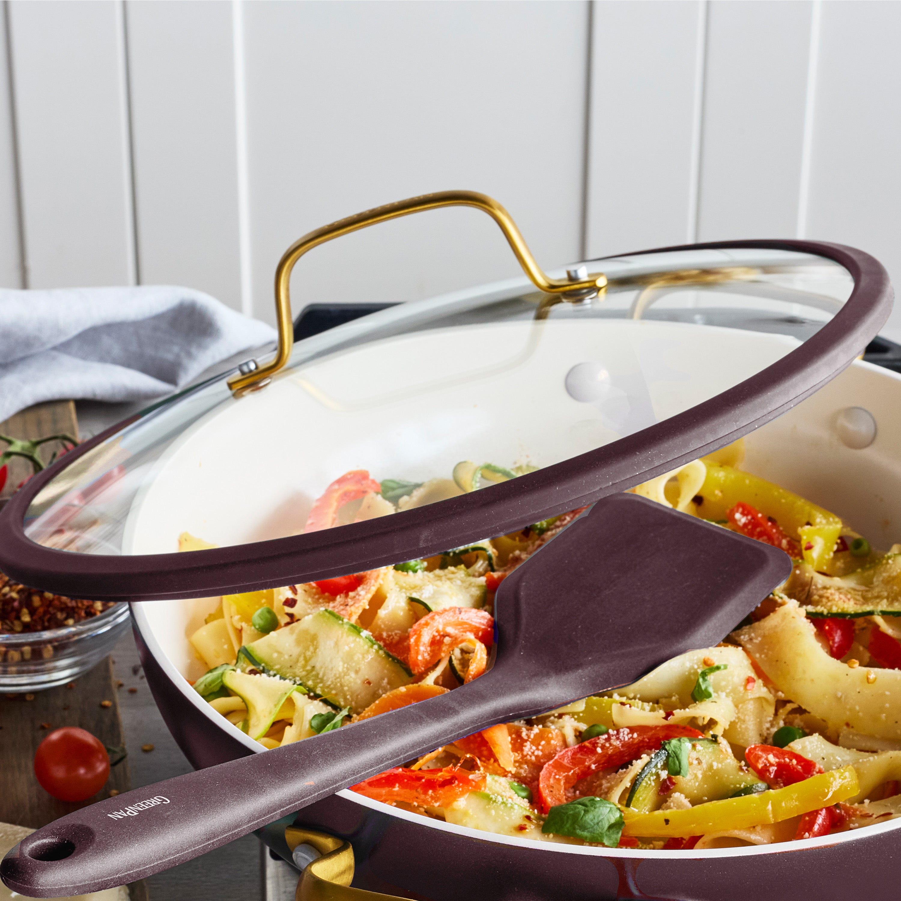 Bordeaux ceramic nonstick everyday pan with lid containing pasta and veggies, spatula resting on the side.