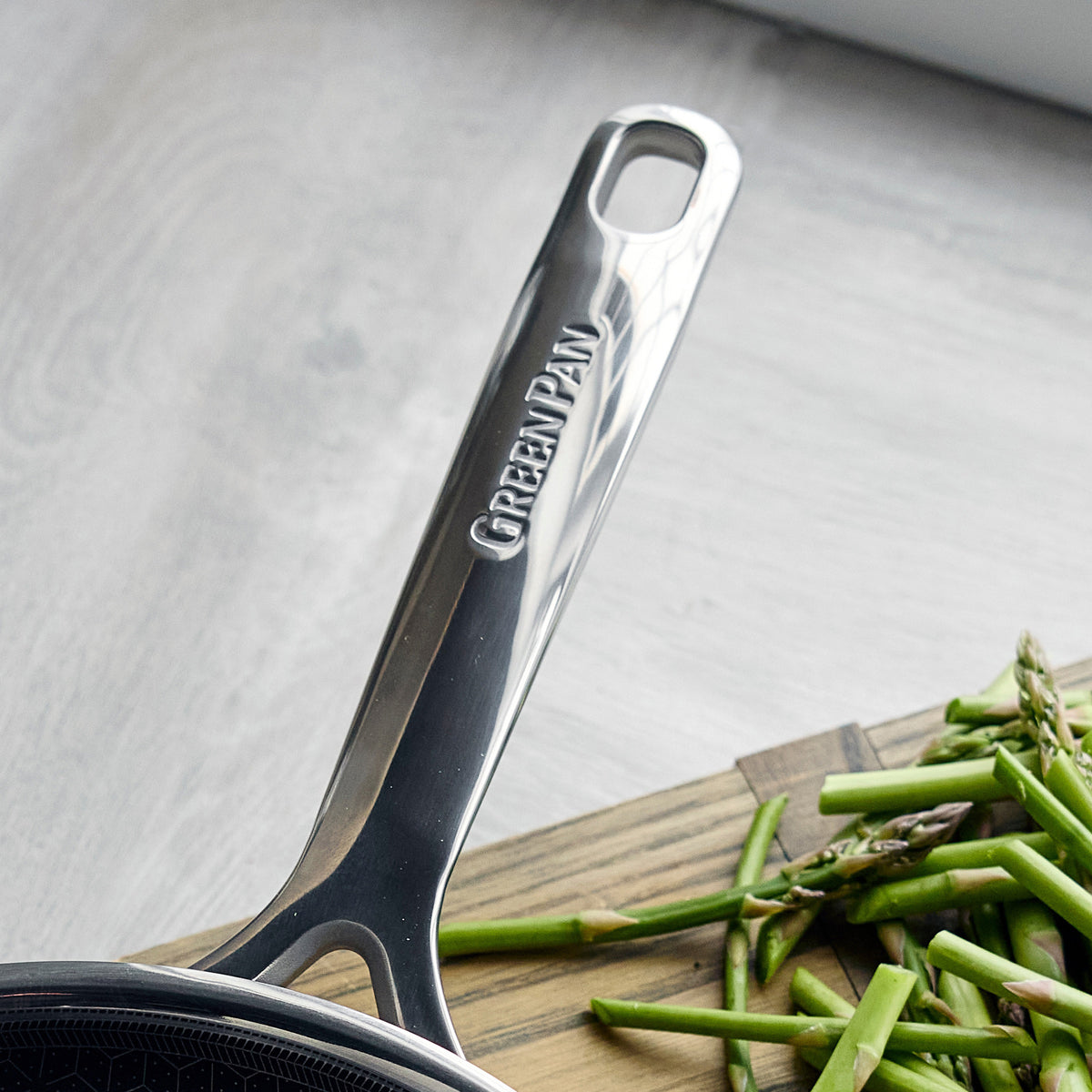 Spectra Diamond Thermobond hybrid ceramic nonstick frypan handle resting on a cutting board next to chopped asparagus.