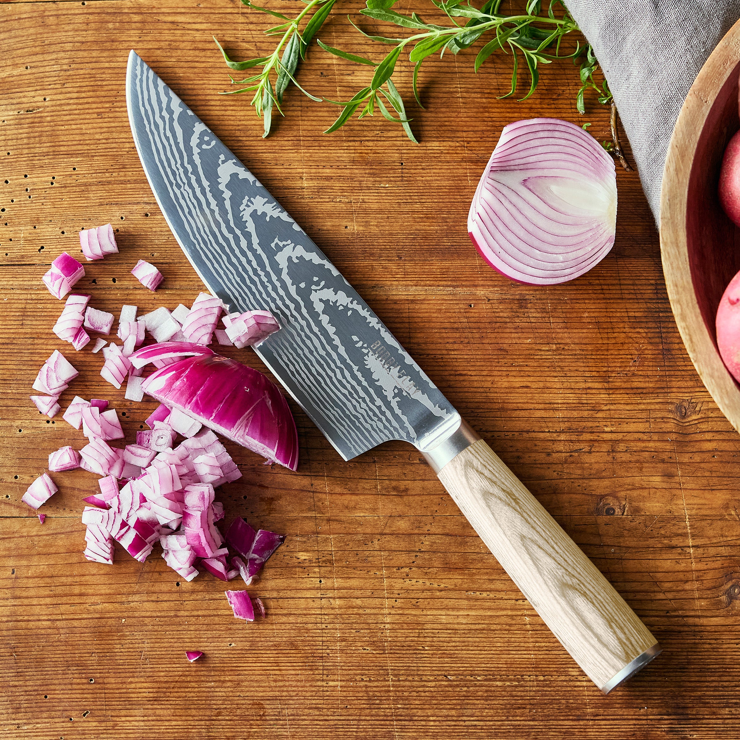 Chef's knife with chopped red onions on a wooden cutting board