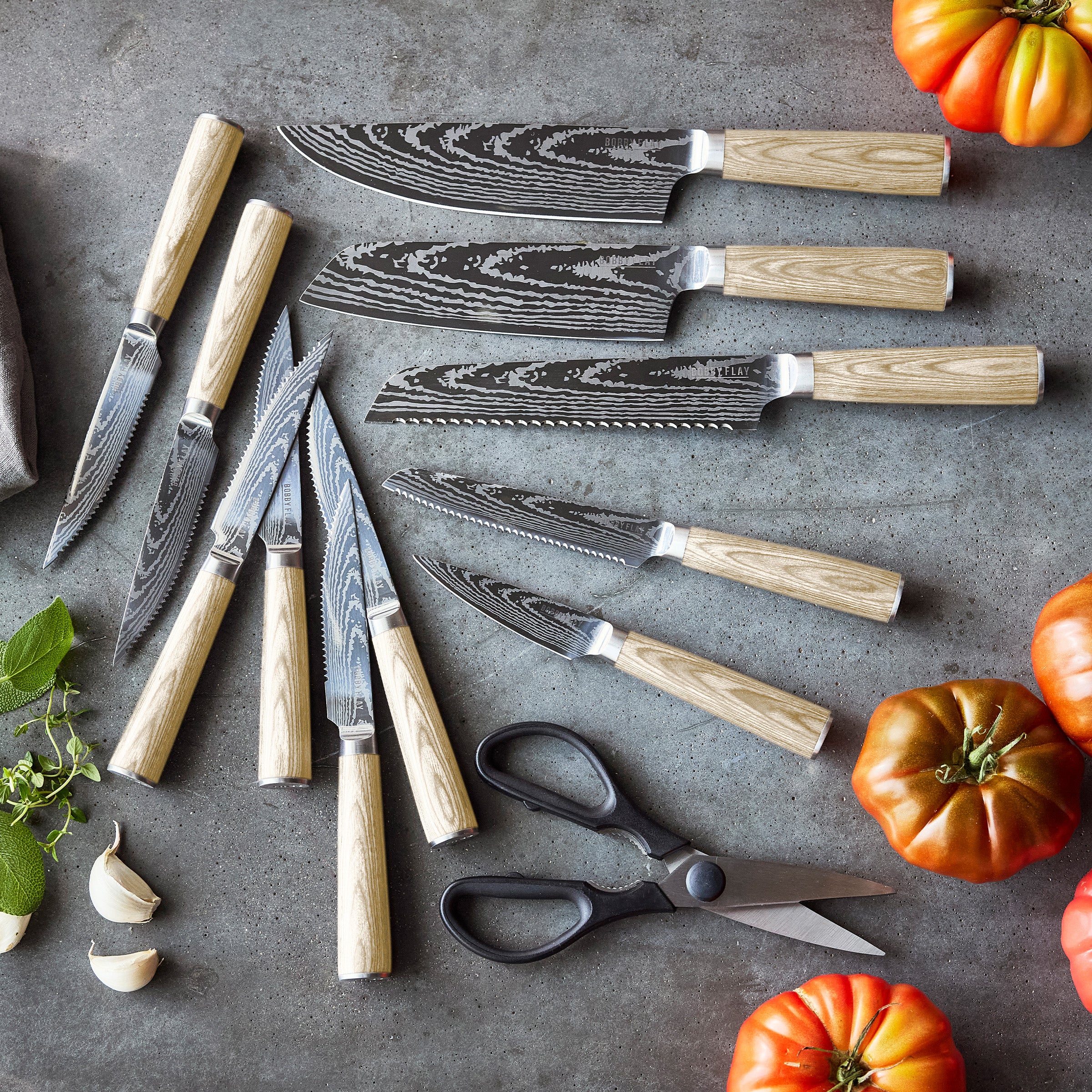 Set of knives with wood print handles on a gray surface with vegetables.