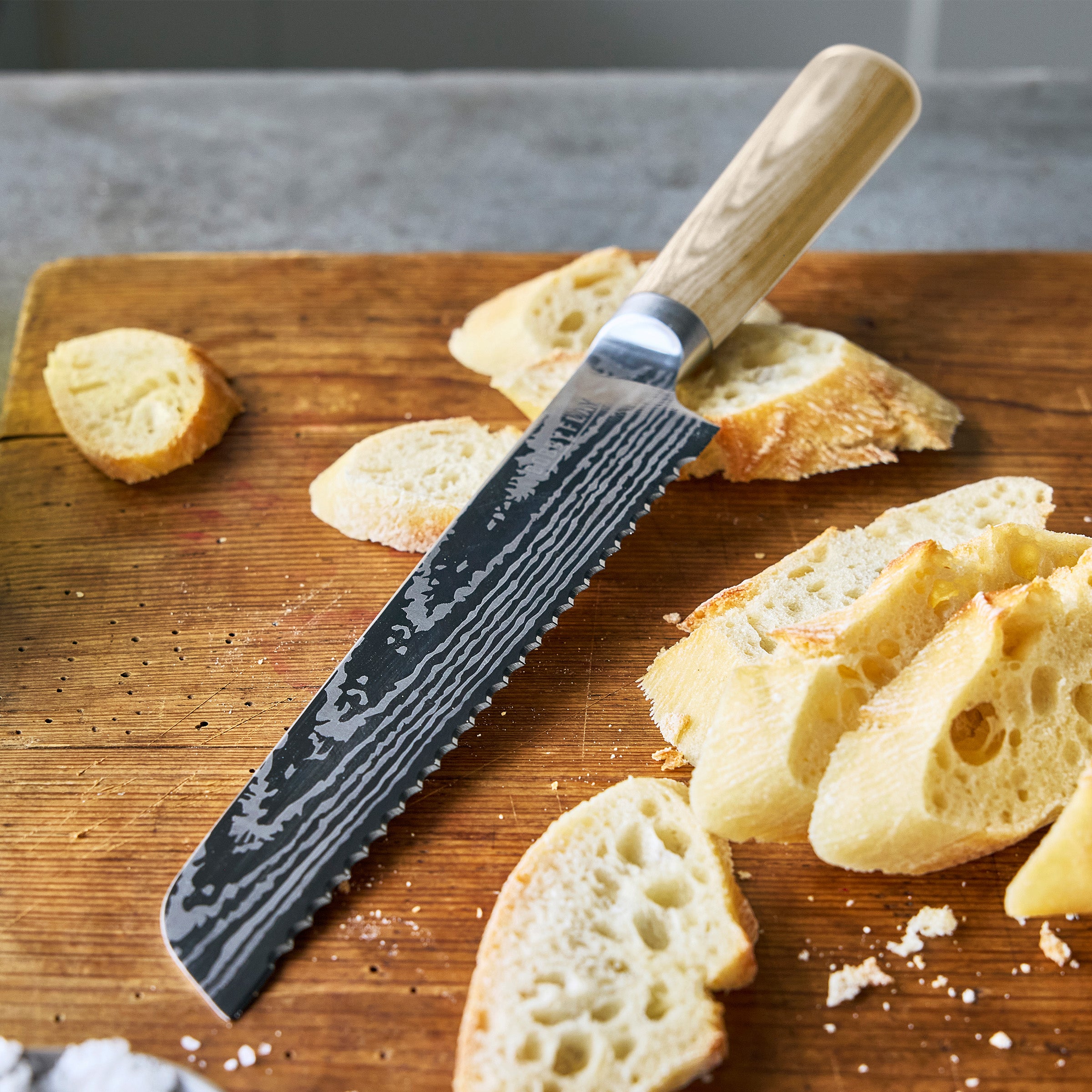 Serrated knife on a wooden cutting board with sliced bread