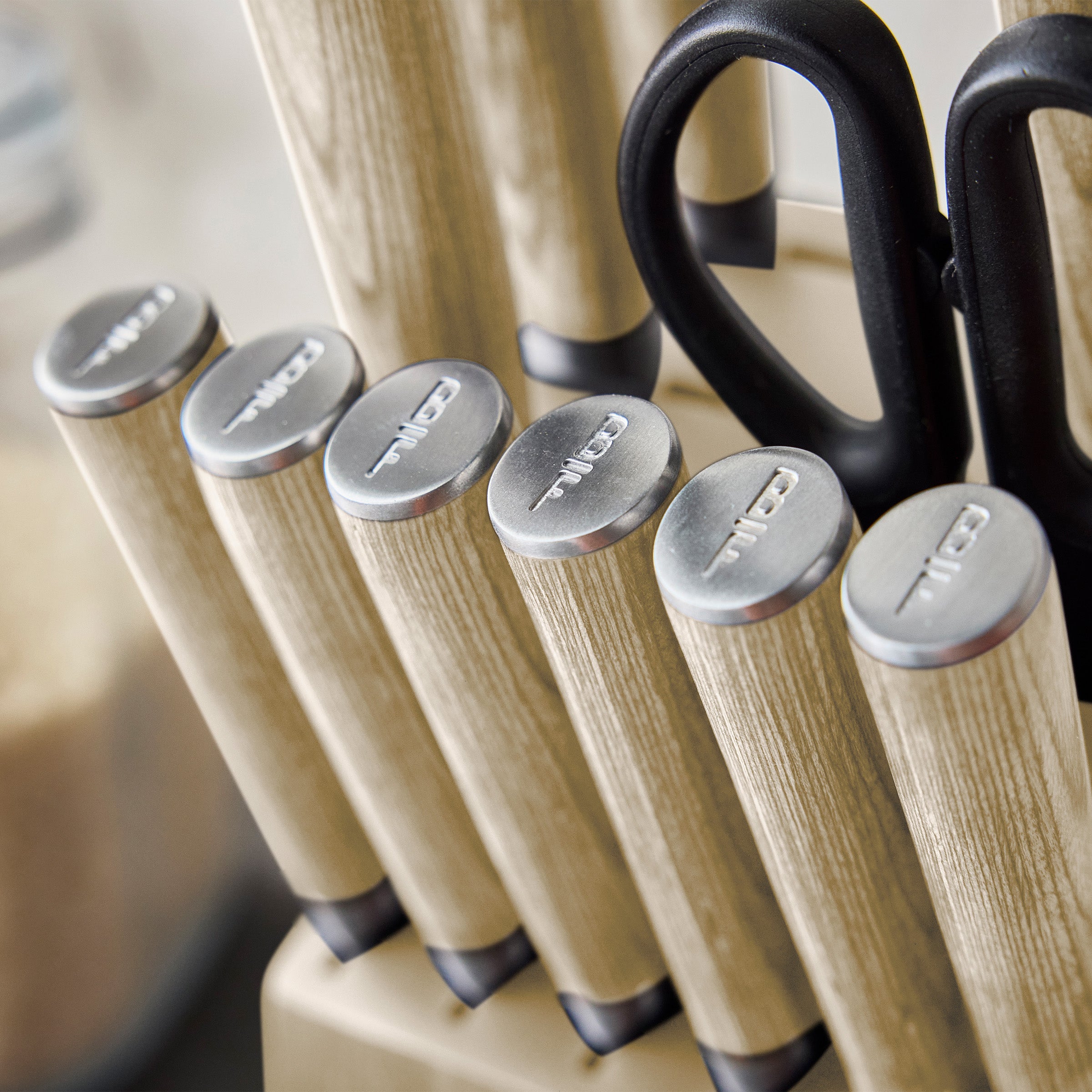 Set of knives with wood print handles and a pair of scissors in a knife block.