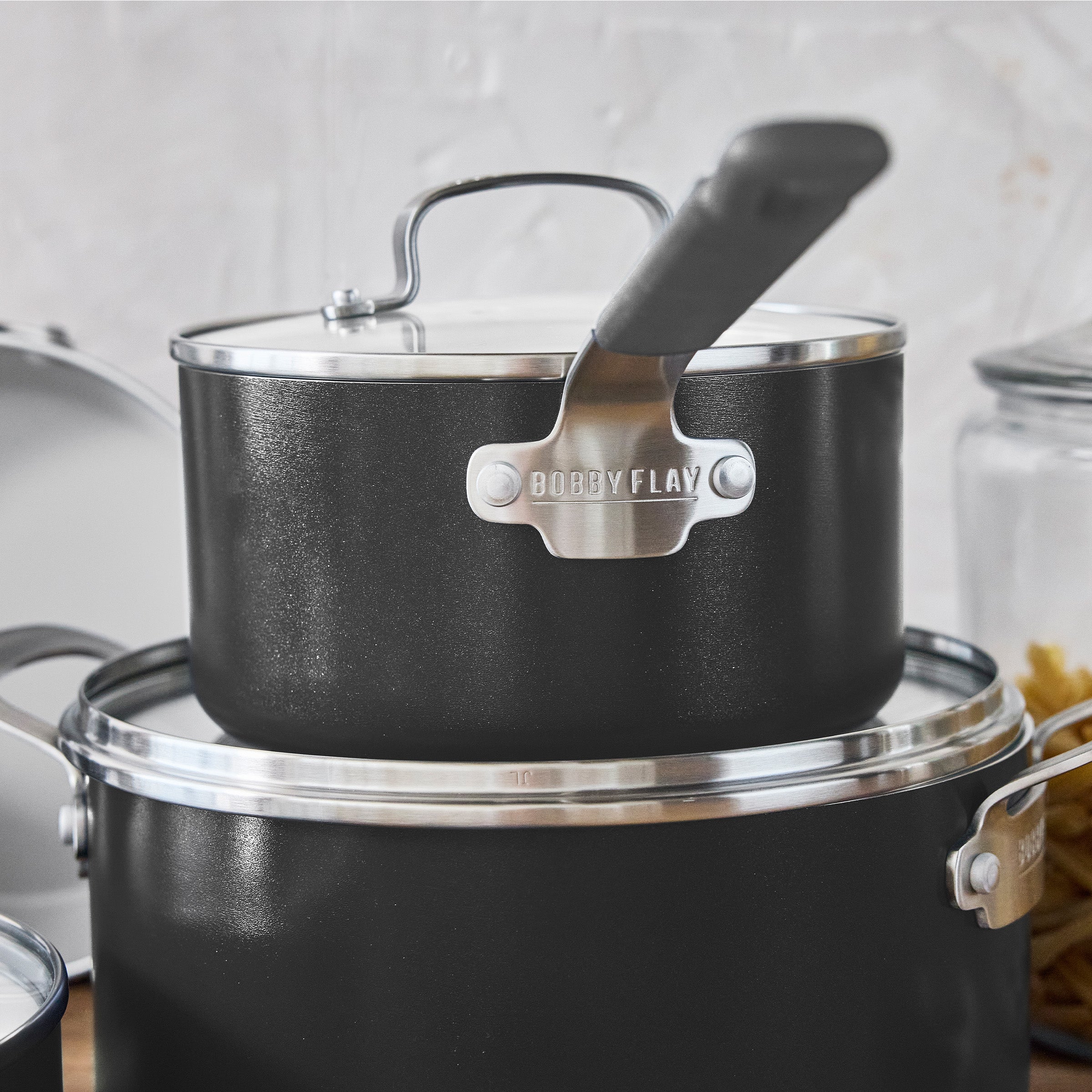 Graphite saucepan with lid stacked on a larger aluminum pot, both from a 10-piece cookware set.