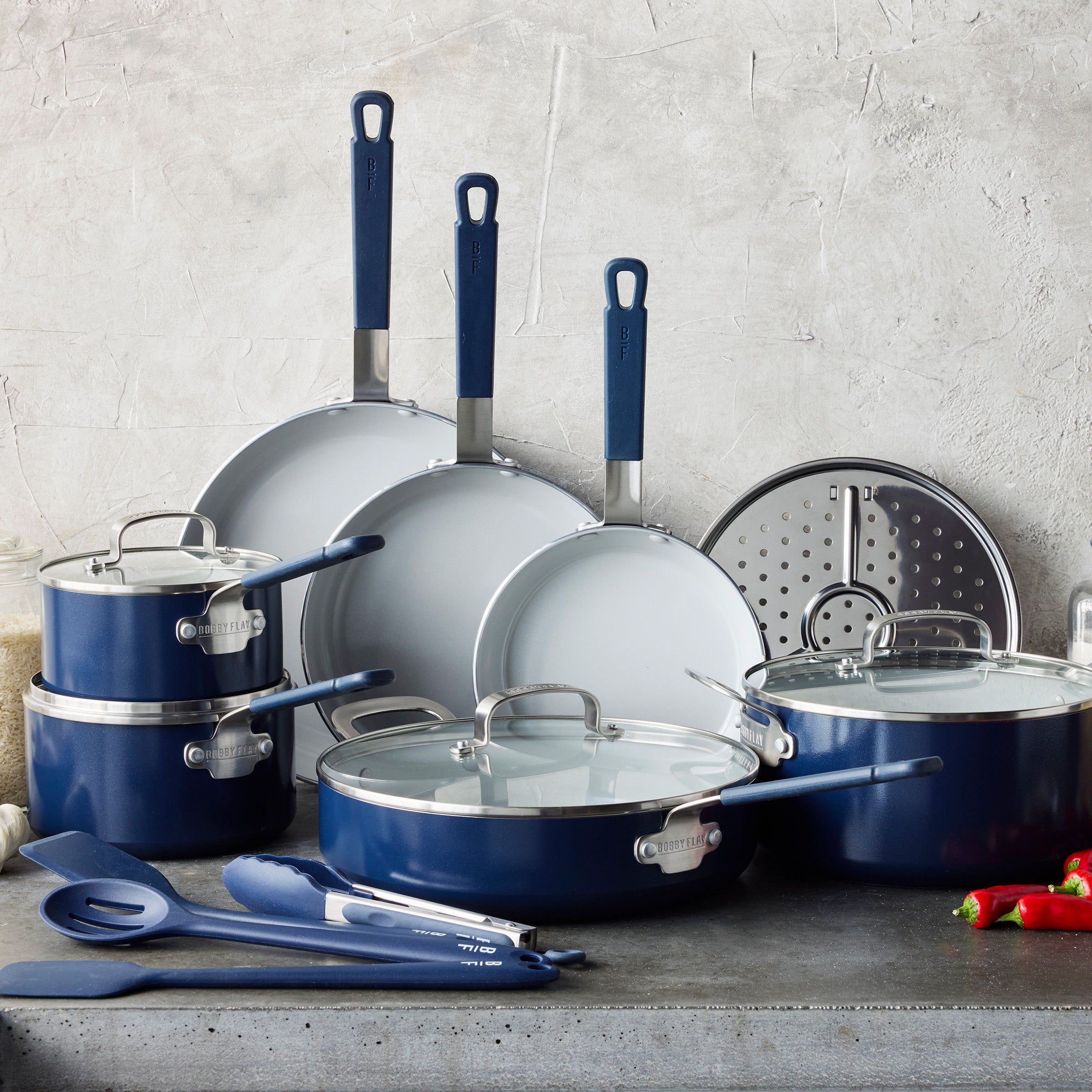 Oxford Blue 16-piece cookware set by Bobby Flay and GreenPan arranged on a countertop with a gray background.
