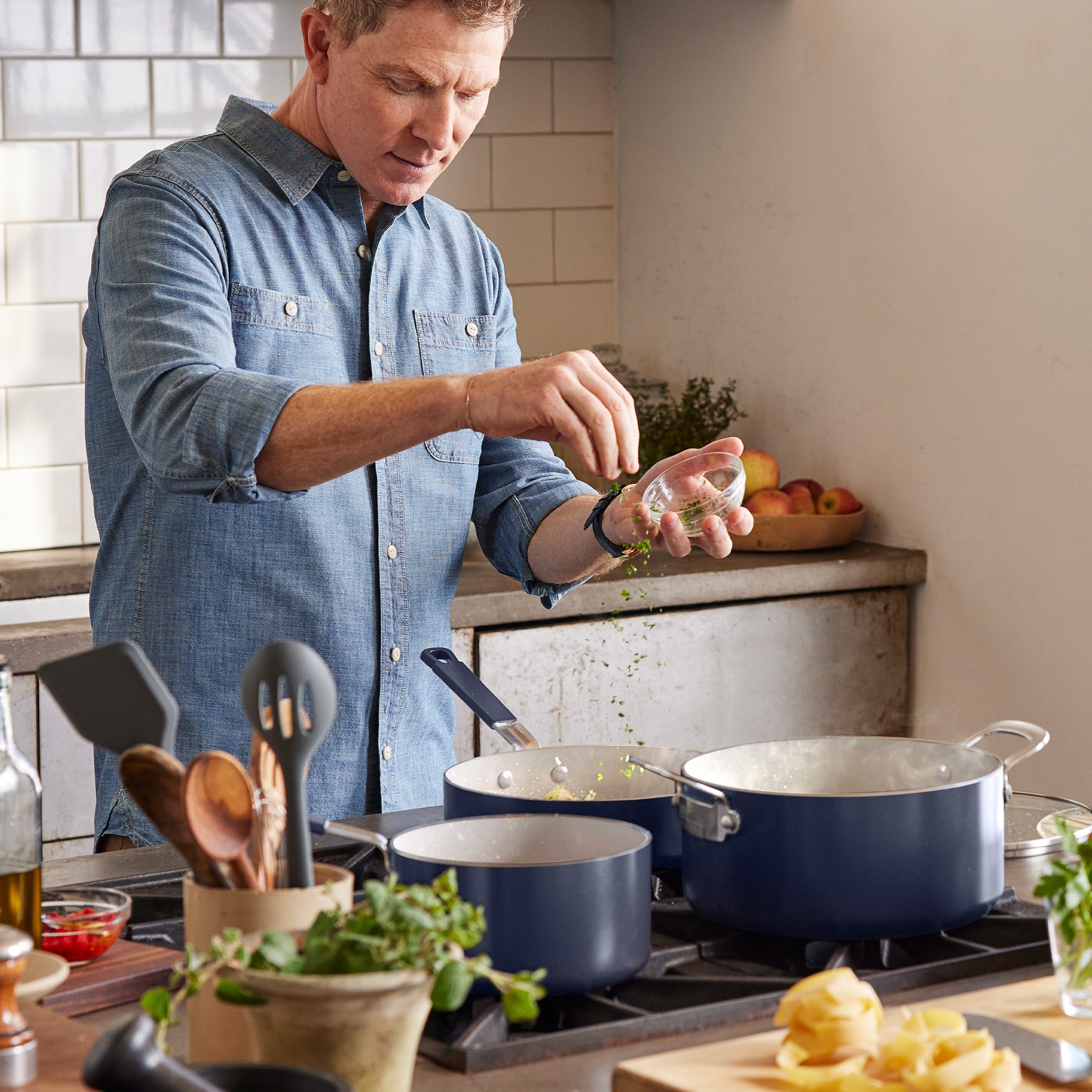 Cooking with the Oxford Blue Bobby Flay by GreenPan 16-piece ceramic nonstick cookware set; herbs being sprinkled into a pan.