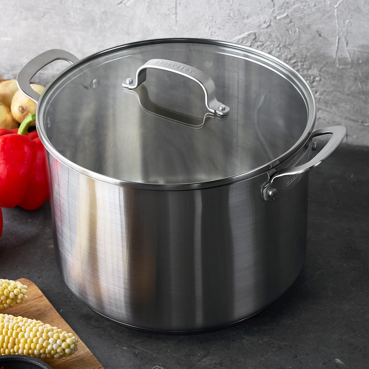 Bobby Flay by GreenPan 12-quart stainless steel stockpot with matching lid and side handles.