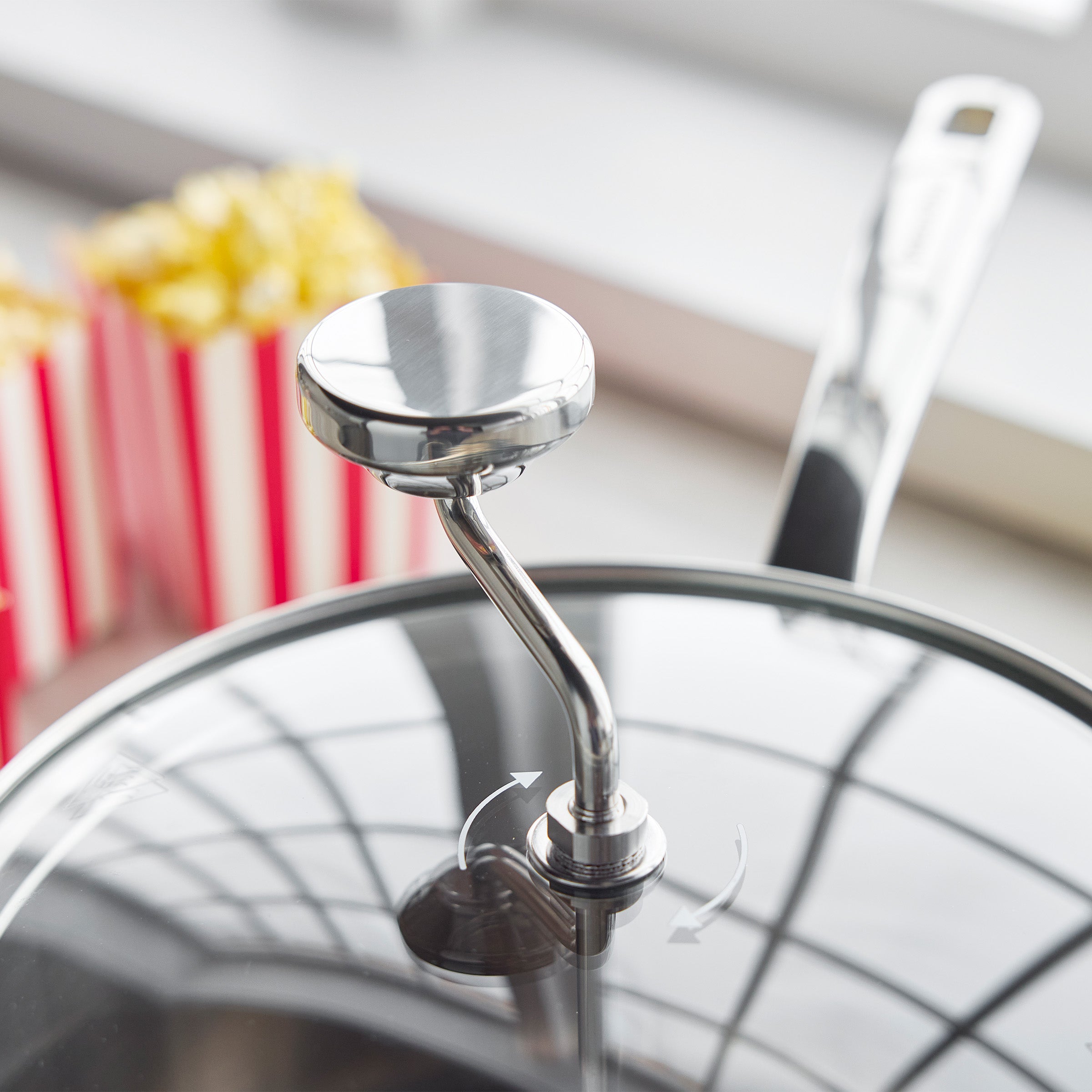 Big Popper Popcorn Maker with a cream lid in front, red-striped popcorn boxes blurred in the background.