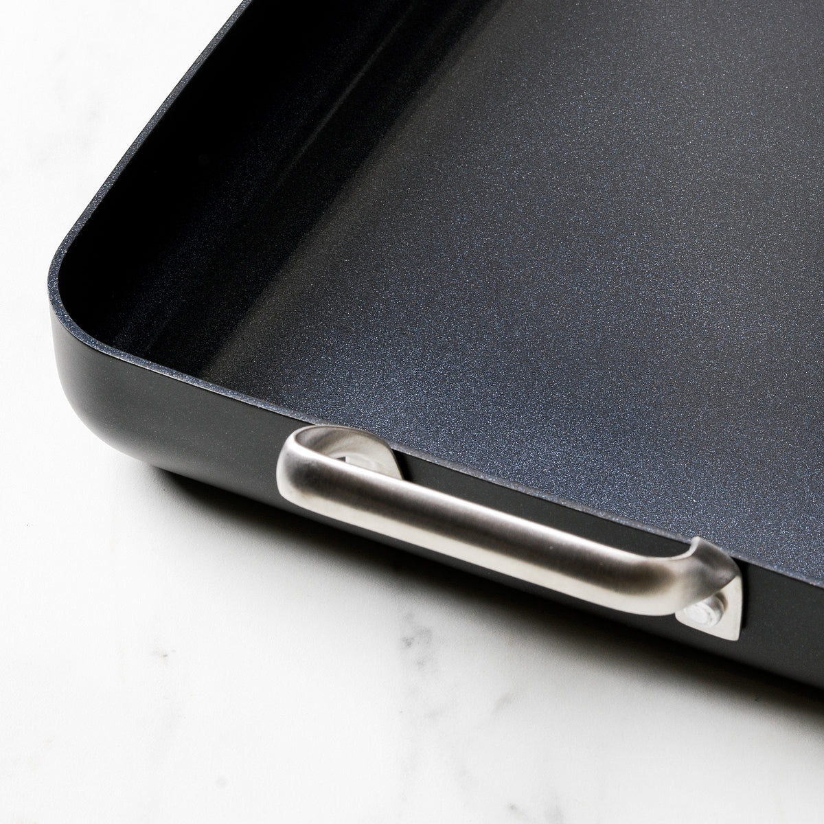 Black aluminum 13.8″ x 10″ rectangular ceramic nonstick roasting pan with metallic side handles on a marble surface.